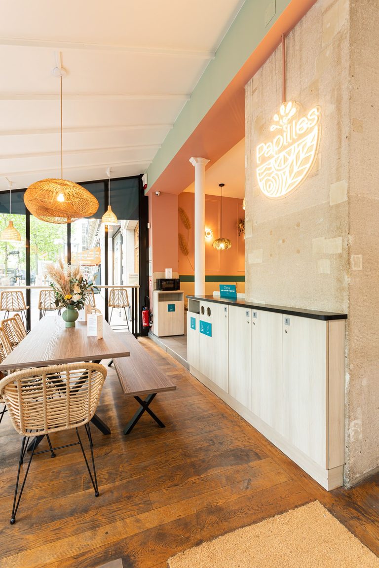 Comptoir bois clair et logo néon du restaurant Papilles à Paris